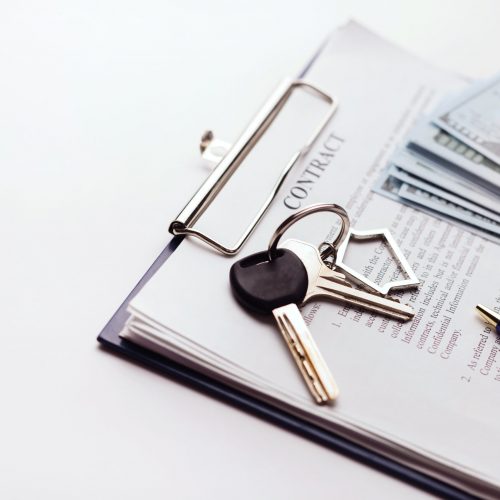 Real estate purchase contract with money and home keys on white table. Rental deal business trip living long term rental. Payment cash